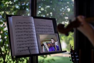 Photo of student playing a violin in front of a music stand with an iPad recording their performance