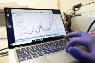 Photo of a person's hand using the pad on a laptop showing images of graphs