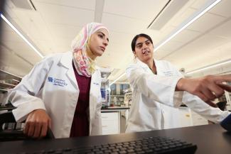 Photo of researchers collaborating with one pointing to a screen off camera